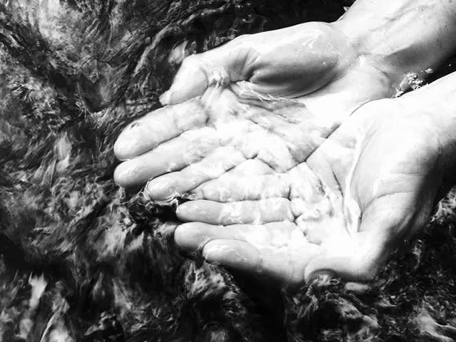 hands cupping water in a stream